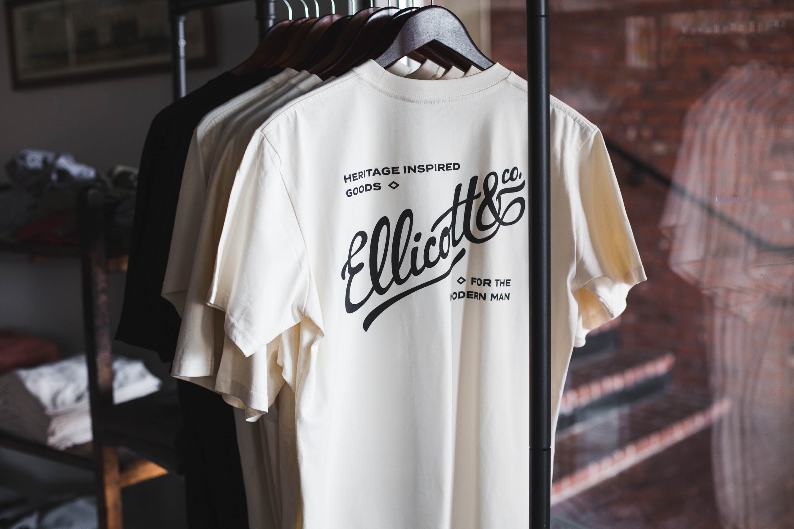 White t-shirt with 'Ellicott & Co' branding on a rack.